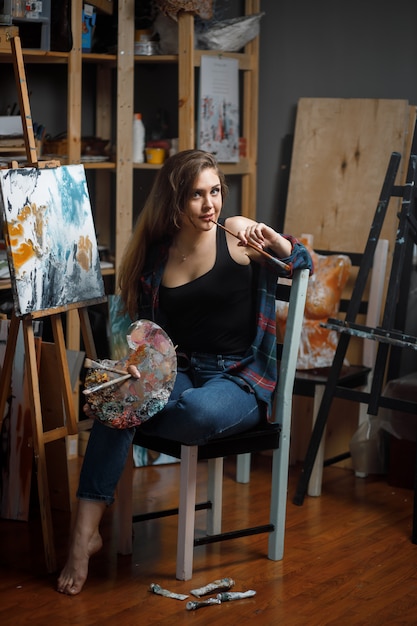 Portrait de jeune artiste entouré de peintures
