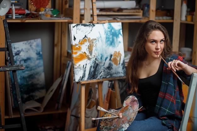 Portrait de jeune artiste entouré de peintures