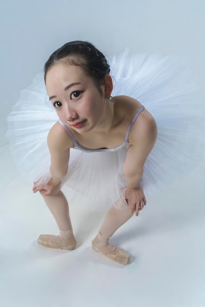Photo portrait d'une jeune ballerine japonaise dans le style anime debout dans une inclinaison appuyée sur ses genoux