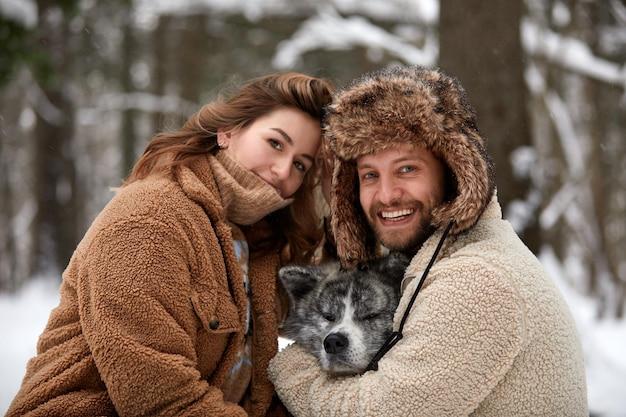 Portrait d'un jeune beau couple d'apparence européenne avec un chien husky dans la forêt d'hiver