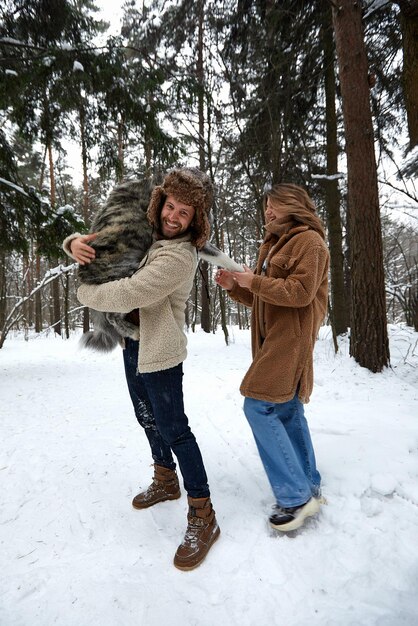 Portrait d'un jeune beau couple d'apparence européenne avec un chien husky dans la forêt d'hiver