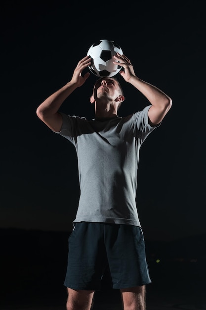 portrait d'un jeune et beau joueur de football talentueux dans une rue jouant avec un ballon de football. Photo de haute qualité