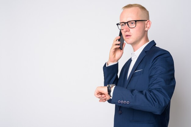 Portrait de jeune bel homme d'affaires aux cheveux blonds courts en costume et lunettes sur blanc