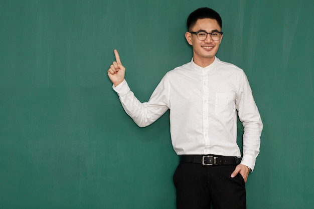 Portrait d'un jeune et bel homme asiatique portant des lunettes et des vêtements d'affaires décontractés, une chemise blanche et un pantalon noir, pose dans des gestes de publicité et présente des choses avec confiance en soi.