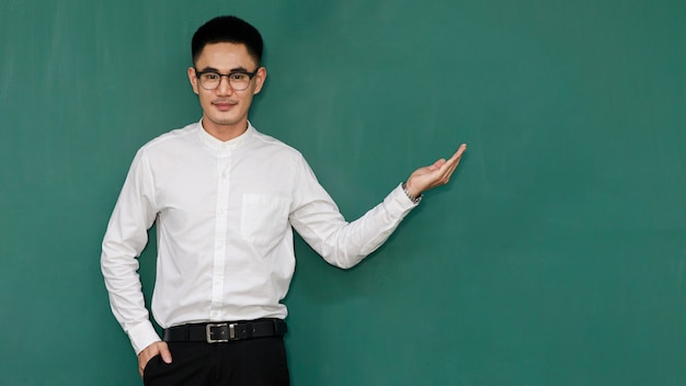 Portrait d'un jeune et bel homme asiatique portant des lunettes et des vêtements d'affaires décontractés, une chemise blanche et un pantalon noir, pose dans des gestes de publicité et présente des choses avec confiance en soi.