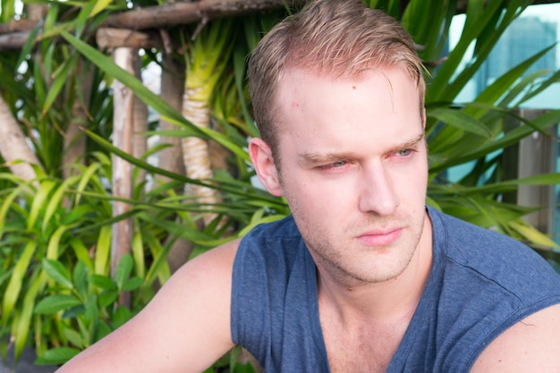 Portrait de jeune bel homme aux cheveux blonds dans la nature à l'extérieur