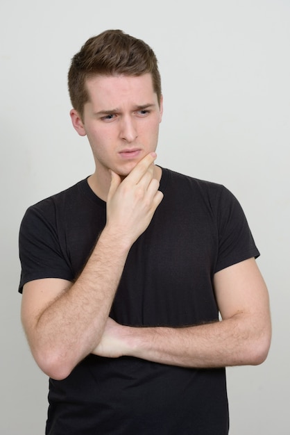 Portrait de jeune bel homme contre le mur blanc