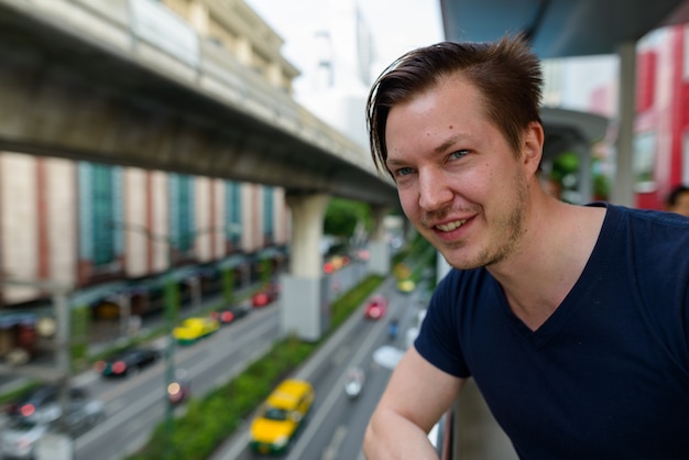 Portrait de jeune bel homme à la gare du ciel dans la ville en plein air