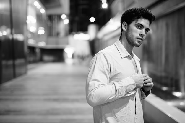 Portrait de jeune bel homme hispanique explorant les rues de la ville pendant la nuit