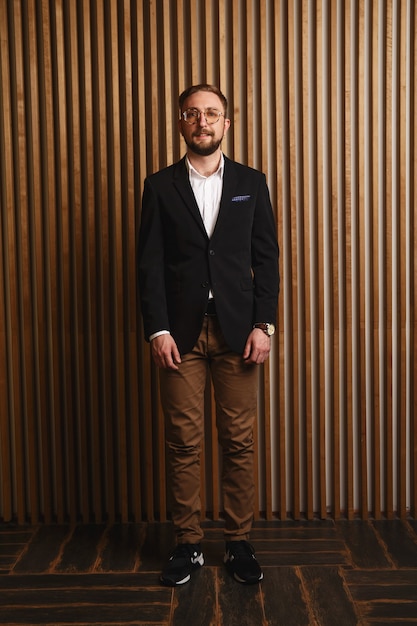 Portrait de jeune bel homme à la mode contre un mur en bois.