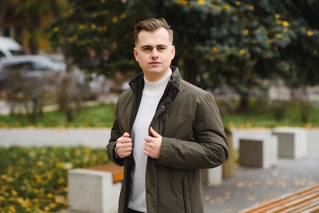 Portrait d'un jeune bel homme, modèle de mode, avec une coiffure moderne en milieu urbain, portant des vêtements décontractés.