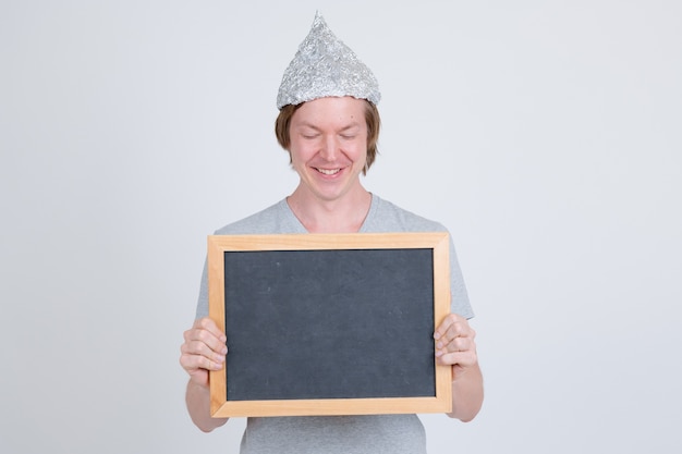 Portrait de jeune bel homme portant chapeau de papier d'aluminium comme concept de théorie du complot sur blanc