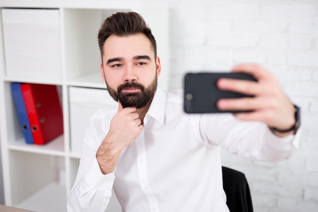 Portrait de jeune bel homme prenant une photo de selfie avec un smartphone