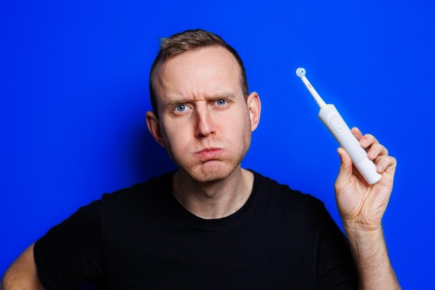 Portrait d'un jeune bel homme se brosser les dents avec une brosse à dents moderne à ultrasons Soins bucco-dentaires Soins matinaux