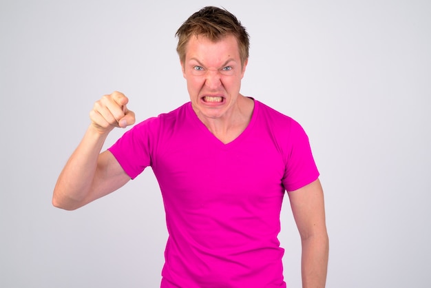 Portrait de jeune bel homme vêtu d'une chemise violette contre le mur blanc