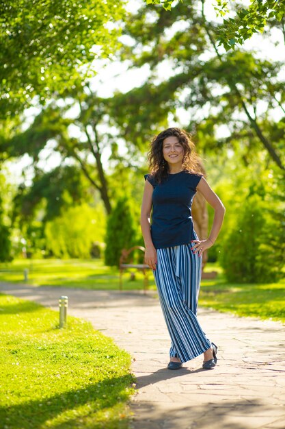 Portrait de jeune belle brune profiter d'une belle journée d'été dans un parc verdoyant.