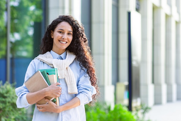 Portrait d'une jeune belle étudiante latino-américaine avec des livres et des cahiers souriant et