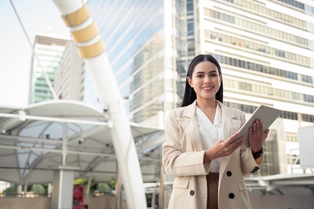 Portrait de jeune belle femme d'affaires à l'aide de tablette dans la ville moderne