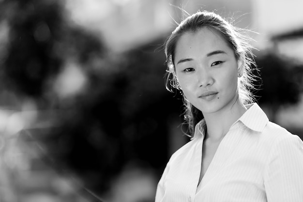 Portrait de jeune belle femme d'affaires asiatique dans les rues à l'extérieur en noir et blanc