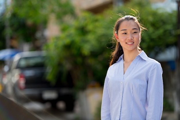 Portrait de jeune belle femme d'affaires asiatique dans les rues à l'extérieur