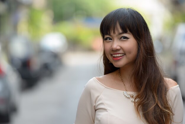 Portrait de jeune belle femme d'affaires asiatique dans la ville en plein air
