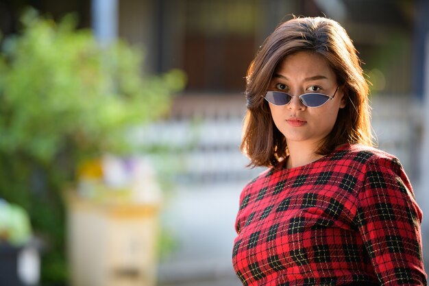 Portrait de jeune belle femme d'affaires asiatique portant des lunettes de soleil dans les rues à l'extérieur