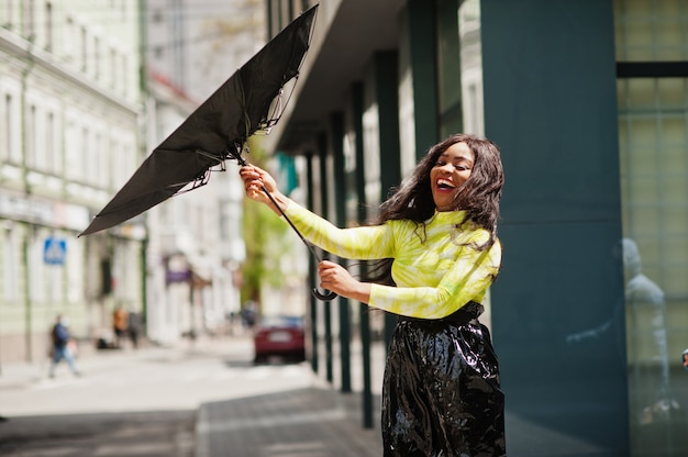 Portrait de jeune belle femme afro-américaine tenant un parapluie noir.