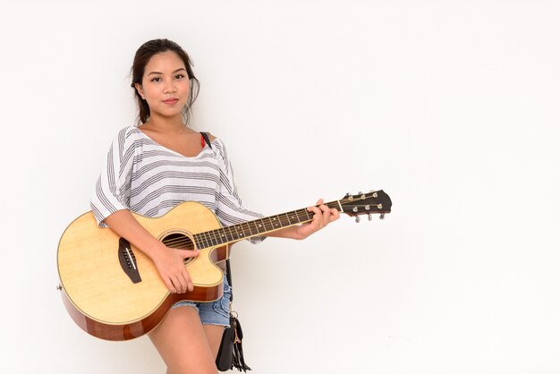 Portrait de jeune belle femme asiatique jouant de la guitare isolé à l'extérieur