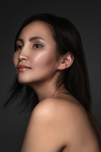 Portrait de jeune et belle femme asiatique sur mur gris
