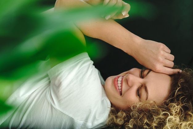 Portrait de jeune et belle femme aux cheveux bouclés allongée sur un canapé vert