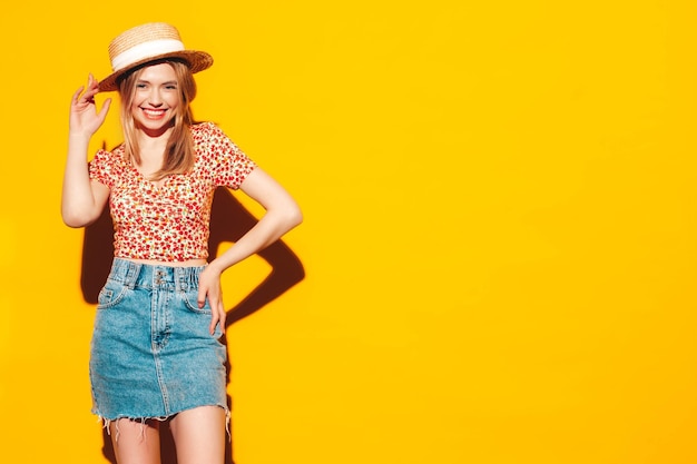 Portrait de jeune belle femme blonde souriante dans des vêtements d'été à la mode femme insouciante posant près d'un mur jaune en studio Modèle positif s'amusant à l'intérieur Gai et heureux Au chapeau