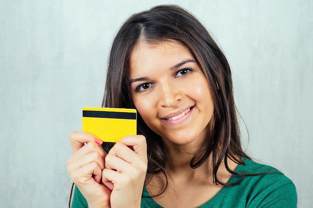 Photo portrait d'une jeune et belle femme brune tenant une carte de crédit dans sa main concept de shopping et de crédit