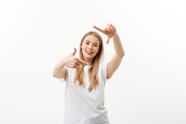 Portrait de jeune belle femme caucasienne avec bonne humeur souriant faisant un cadre de caméra avec les doigts.