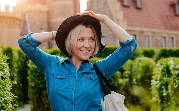 Portrait jeune belle femme heureuse à la mode dans un chapeau noir dans la vieille ville médiévale.