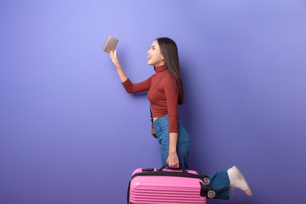 Portrait de jeune belle femme heureuse voyage à bord avec passeport sur violet isolé