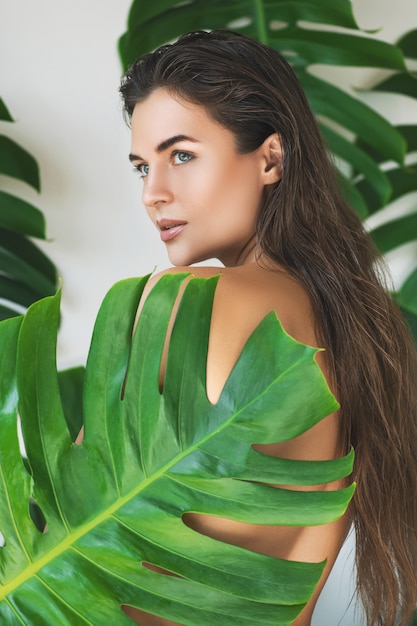 Portrait de jeune et belle femme avec une peau lisse parfaite dans les feuilles tropicales