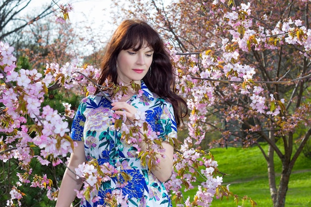 portrait de jeune belle femme posant avec des fleurs de sakura dans le parc