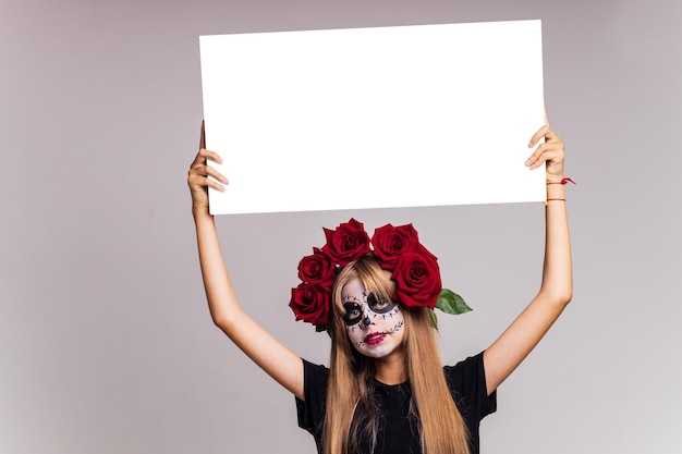 Portrait de jeune belle fille avec squelette de maquillage sur son visage et roses rouges sur la tête