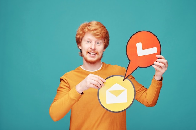 Portrait de jeune blogueur rousse souriant montrant comme une bannière contre le mur bleu