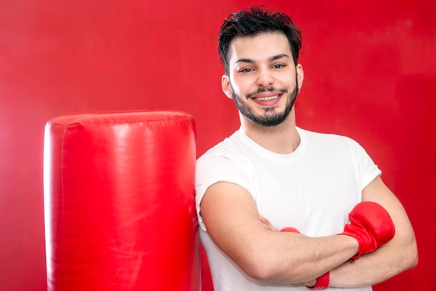 Portrait De Jeune Boxeur Barbu Souriant Posant Par Sac De Boxe Dans Un Gymnase