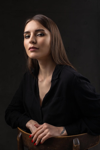 Portrait d'une jeune brune aux cheveux longs en studio Photo dramatique dans des couleurs sombres Une fille avec un tatouage de serpent sur son bras