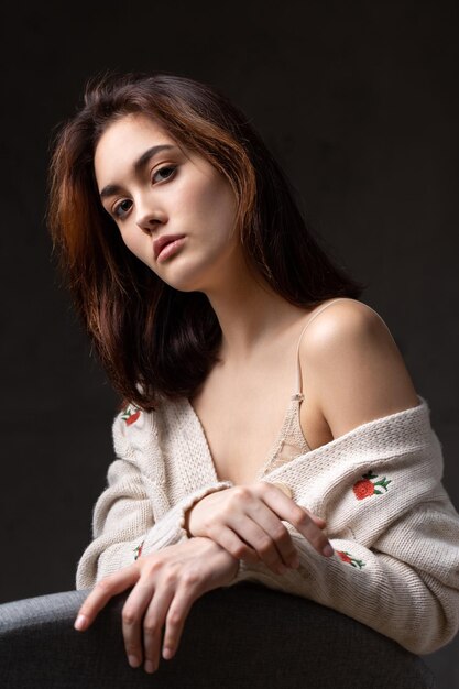 Portrait d'une jeune brune aux cheveux longs en studio photo dramatique dans des couleurs sombres