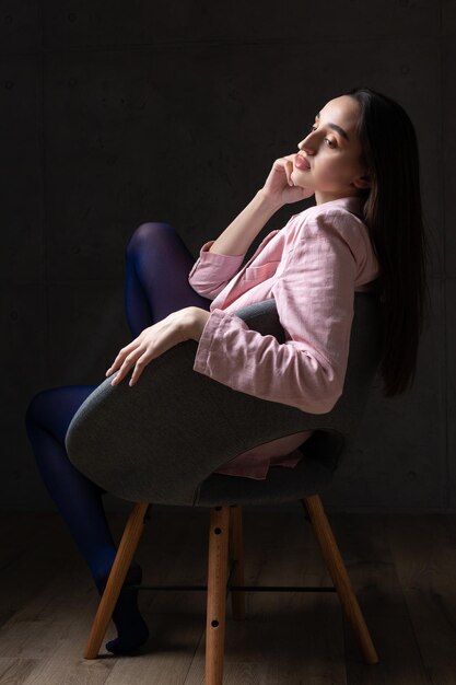 Portrait d'une jeune brune aux cheveux longs en studio photo dramatique dans des couleurs sombres