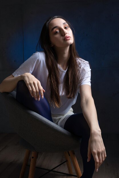 Portrait d'une jeune brune aux cheveux longs en studio photo dramatique dans des couleurs sombres