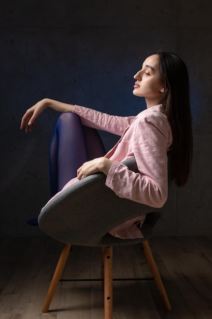 Portrait d'une jeune brune aux cheveux longs en studio photo dramatique dans des couleurs sombres