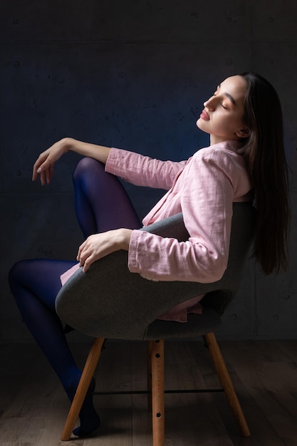 Portrait d'une jeune brune aux cheveux longs en studio photo dramatique dans des couleurs sombres