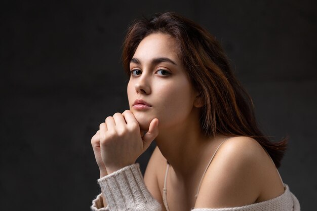 Portrait d'une jeune brune aux cheveux longs en studio photo dramatique dans des couleurs sombres