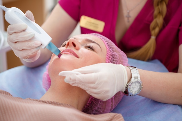 Portrait d'une jeune cliente venue chez l'esthéticienne pour une cure thermale sur son visage (massage, gommage et masque). Concept de beauté et de soins personnels