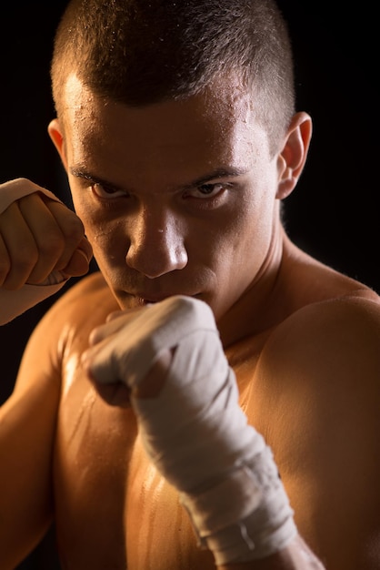 Portrait d'un jeune combattant sur fond noir.