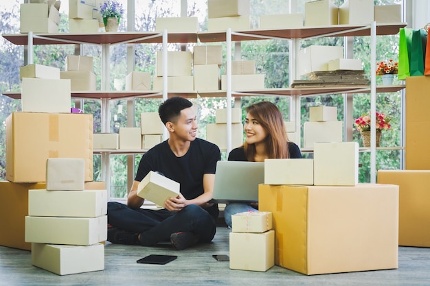 Photo portrait de jeune couple d'affaires asiatiques heureux à l'aide de smartphone et ordinateur portable pour recevoir la commande